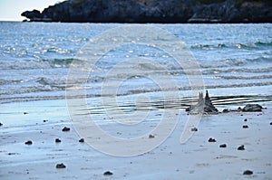 Dark grey black sand castles on wet local beach in sunny day in wide angle