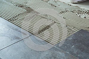 Ceramic floor tiles laid on applied adhesive