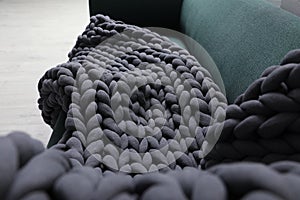 Dark grey chunky knit blanket on sofa indoors, closeup