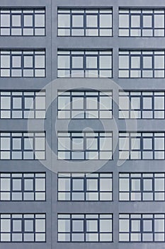 Dark grey facade of building with grey big windows. Apartment block