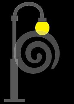 A dark grey gray street light lamp with yellow incandescent bulb black backdrop