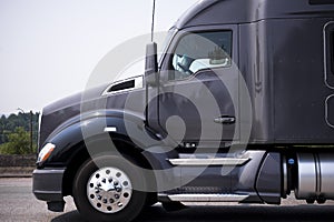 Dark grey powerful modern big rig semi truck tractor profile run