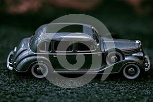 Dark grey vintage car . Retro car`s close up.Retro car on a dark background. Car close-up.Small toy retro car of gray color. Retr