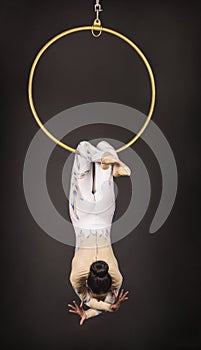 Dark-haired aerial acrobat in a white suit on a dark background