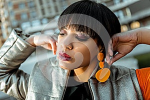 Dark-haired appealing girl showing her orange plastic earrings