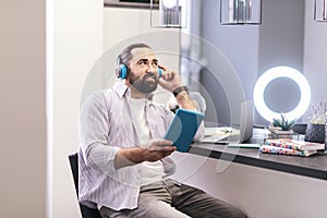 Dark-haired bearded man in earphones listening to music on a tablet