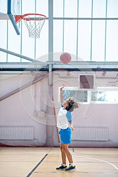 Dark-haired boy in sportswear throwing the ball into the ring