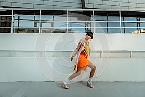 Dark-haired girl with bangs theatrically posturing against white wall