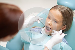 Dark-haired girl opening mouth while visiting dentist