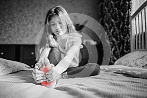 A dark-haired girl in a white blouse and blue jeans is massaging her leg