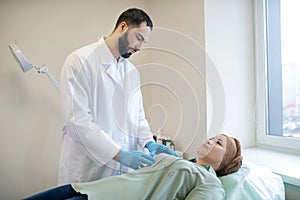 Dark-haired mammologist examining breasts of his patient