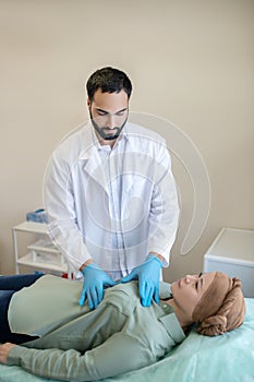 Dark-haired mammologist palping breasts of his patient