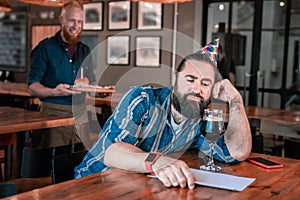 Dark-haired man feeling cheerless waiting for friends on birthday