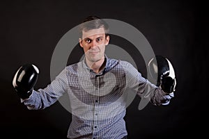 Dark-haired man in a plaid shirt with boxing gloves on his hands stabs