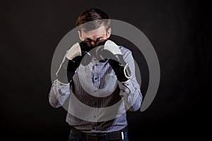 Dark-haired man in a plaid shirt with boxing gloves on his hands in stance