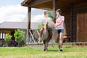 Dark-haired mother teaching her daughter riding a horse