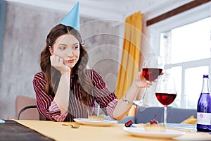 Dark-haired woman clanging glasses of wine with friend