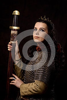 A dark-haired woman with a sword and crown, a Scandinavian warrior in a chain mail against