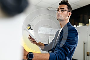 Dark-haired young architect dressed in blue checkered jacket works in the modern office