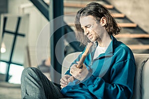 Dark-haired young man being unsatisfied with sound of his guitar