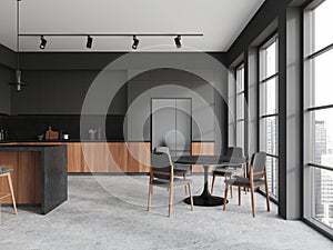 Dark home kitchen interior with dining table, cooking space and panoramic window
