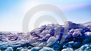 Dark ice blocks in a heap. Northern landscape. Broken ice drift with violet purple toning. Sunny North wallpaper with