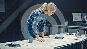 In the Dark Industrial Design Engineering Facility: Female Engineer Works with Blueprints Laying o