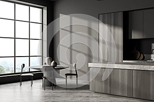 Dark kitchen interior with eating table and chairs on concrete floor