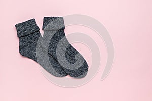 Dark knitted socks on a light pink background. Minimal footwear concept