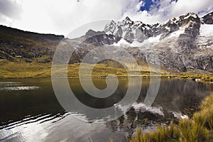 Dark lake in foot of snow-covered mountain at sunrise