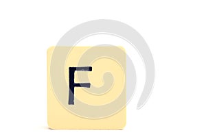 Dark letter F on a pale yellow square block isolated on white background