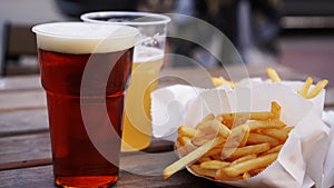 Dark and light beer and fries on a wooden table. Food court. Takeaway food