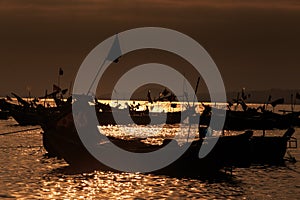 Dark Boat Silhouettes against Sunset Reflection on Ocean Water