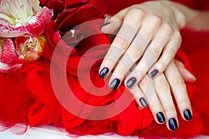 Dark manicure and flowers on red