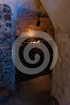 Dark medieval wine cellar. Bottles stacked by the wall