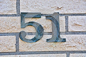 A dark metallic digit fixed on a wall and showing the number fifty one