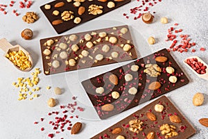 Dark and milk chocolate bars with nuts and dried fruits on light background. Homemade organic chocolate. Handmade tasty presents.