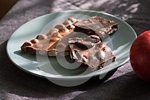 Dark and milk chocolate with nuts and apple on a plate