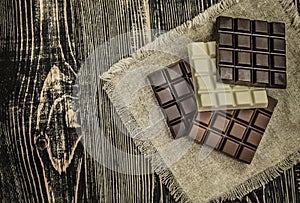 Dark , milk and white chocolate bar. Chocolate over rustic wooden background