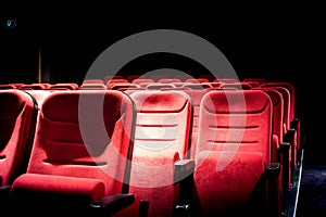 Dark movie theater with projection light and empty red seats