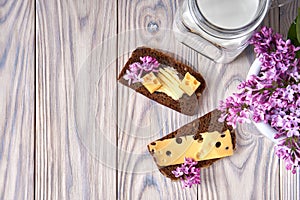 Dark multigrain bread made from rye, wheat, oats, barley with sunflower, flax seeds. Milk, cheese, butter. Lilac flowers, rustic