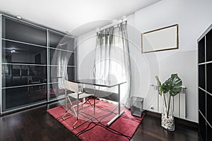 Dark office desk area in bedroom with sliding glass wardrobe,