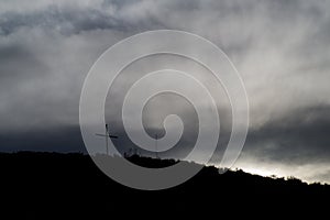 Dark photo of some clouds at sunset with a cross