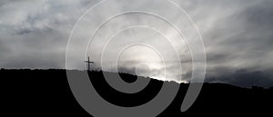 Dark photo of some clouds at sunset with a cross