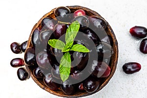 Dark pink-red ripe Syzygium cumini fruits. Dark black java plum in a wood bowl at isolated white background. Green mint leaf on