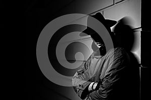 dark portrait of a man in a raincoat with a hat at night on the street