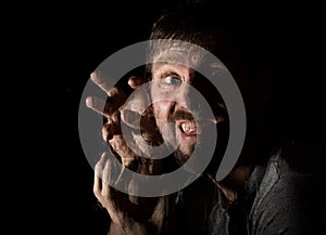 Dark portrait of scary bearded man with smirk, expresses different emotions. Drops of water on a glass, hand and male