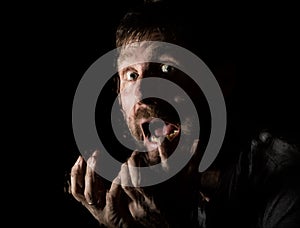 Dark portrait of scary bearded man with smirk, expresses different emotions. Drops of water on a glass, hand and male