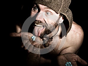 Dark portrait of scary evil sinister bearded man with smirk, holds in palm of a bunch of pills. strange Russian man with