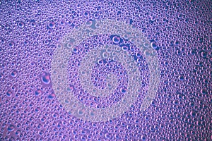 Dark purple abstract background of bright foam bubbles. Water drops on blue surface. Pink texture of shiny glass. Drops pattern. T